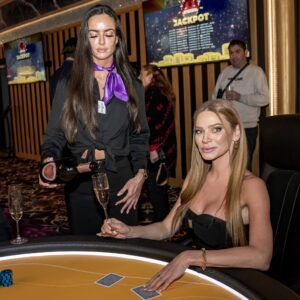 Servírka nalévající šampaňské hráčce u pokerového stolu v kasinu Vestec