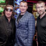 tri-muzi-pred-hracimi-automaty-v-kasinu-vestec-vsichni-se-usmivaji Tři muži před hracími automaty v kasínu Vestec, všichni se usmívají