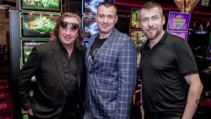 Tři muži před hracími automaty v kasínu Vestec, všichni se usmívají